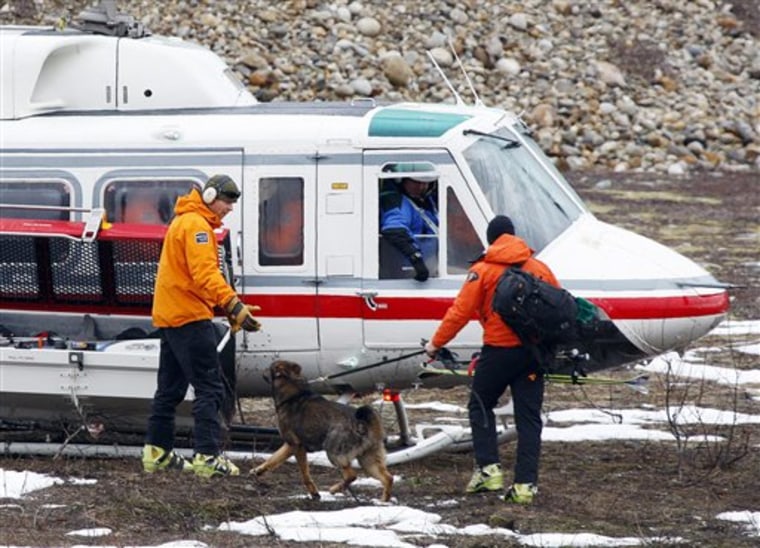 A Royal Canadian Mounted Police officer and his dog board a helicopter Sunday on their way out to the area where a large avalanche struck near Revelstoke, British Columbia.